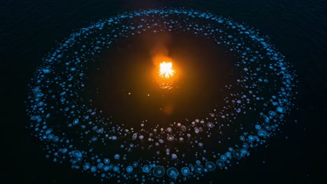 a stunning aerial view of a fiery flame surrounded by a mesmerizing circle of bioluminescent jellyfish illuminating the dark waters below