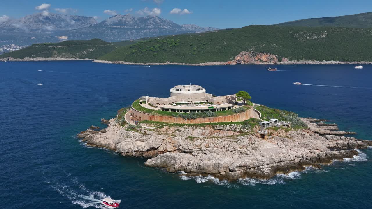 Mamula Island Hotel And Fortress On Rocky Islet In Boka Bay, Montenegro. Lush Green Hills And Mountains In Background. aerial pullback shot