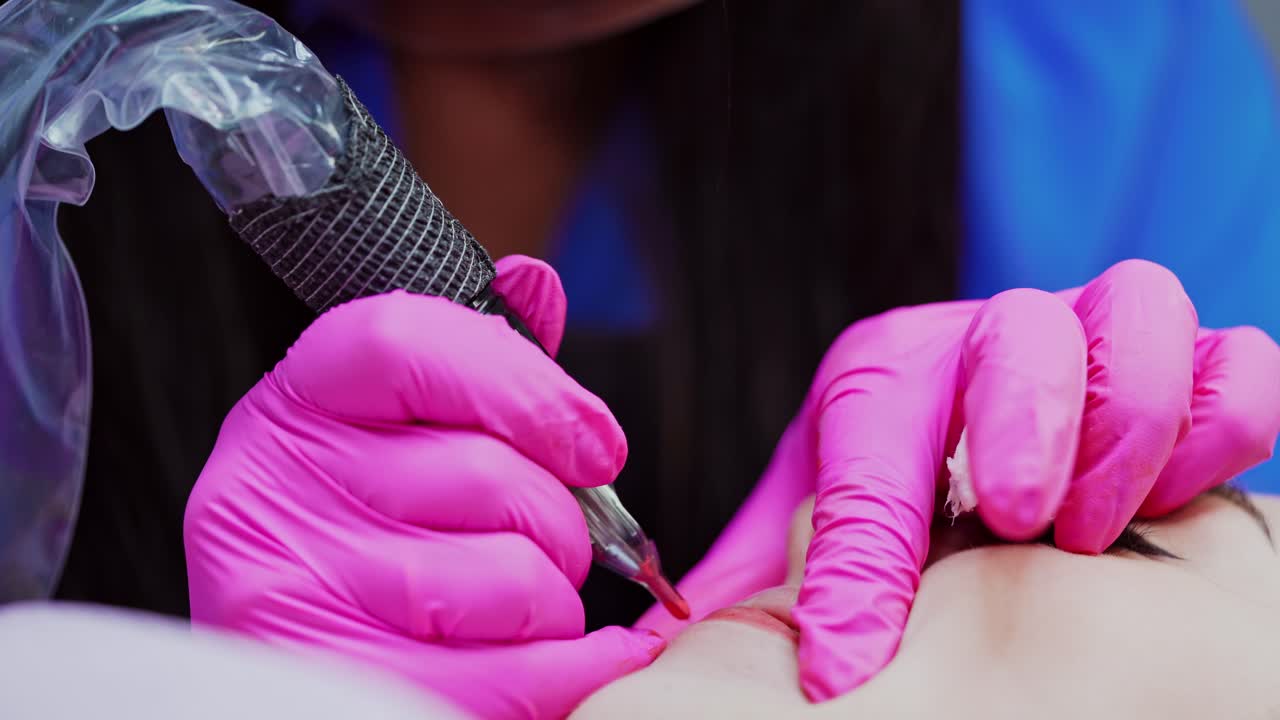 Cosmetology procedure on lips. Modern tattoo machine in beautician hands during the permanent make-up on lips.