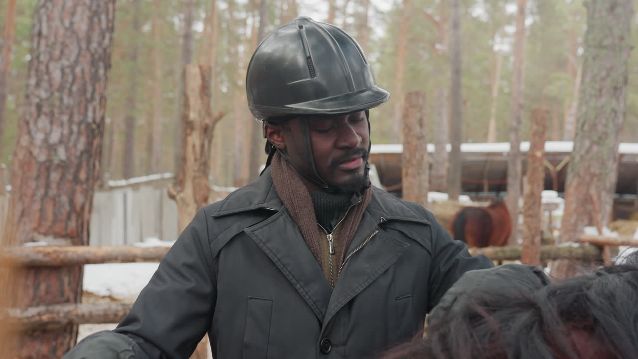 Cuidador de caballos vigilando una zona exterior; trabajador de rancho observando caballos entre vallas y árboles; supervisor de granja dedicado a evaluar la seguridad y el estado del ganado y el entorno