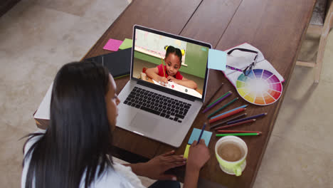 Caucasian-female-teacher-using-laptop-on-video-call-with-schoolgirl,-making-notes