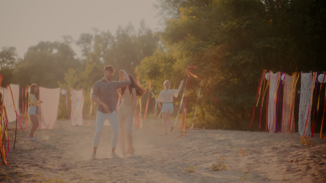 친구 들 이 리본 을 들고 춤 을 추는 동안 바카타 를 하는 젊은 부부