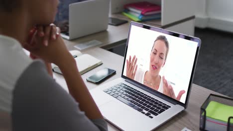 mujer afroamericana teniendo una videoconferencia en una computadora portátil con una colega de oficina en la oficina