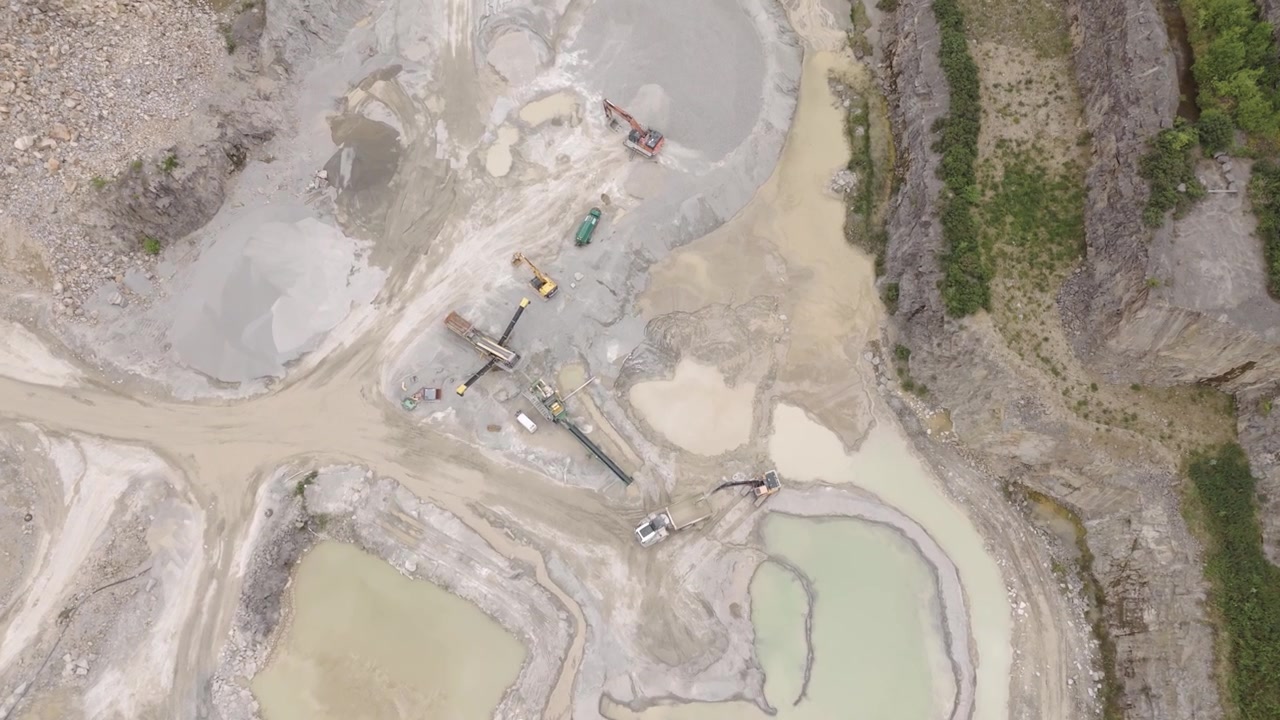 Top-down aerial view of a large mining operation in the pit of an aggregate quarry, showcasing the extensive excavation work