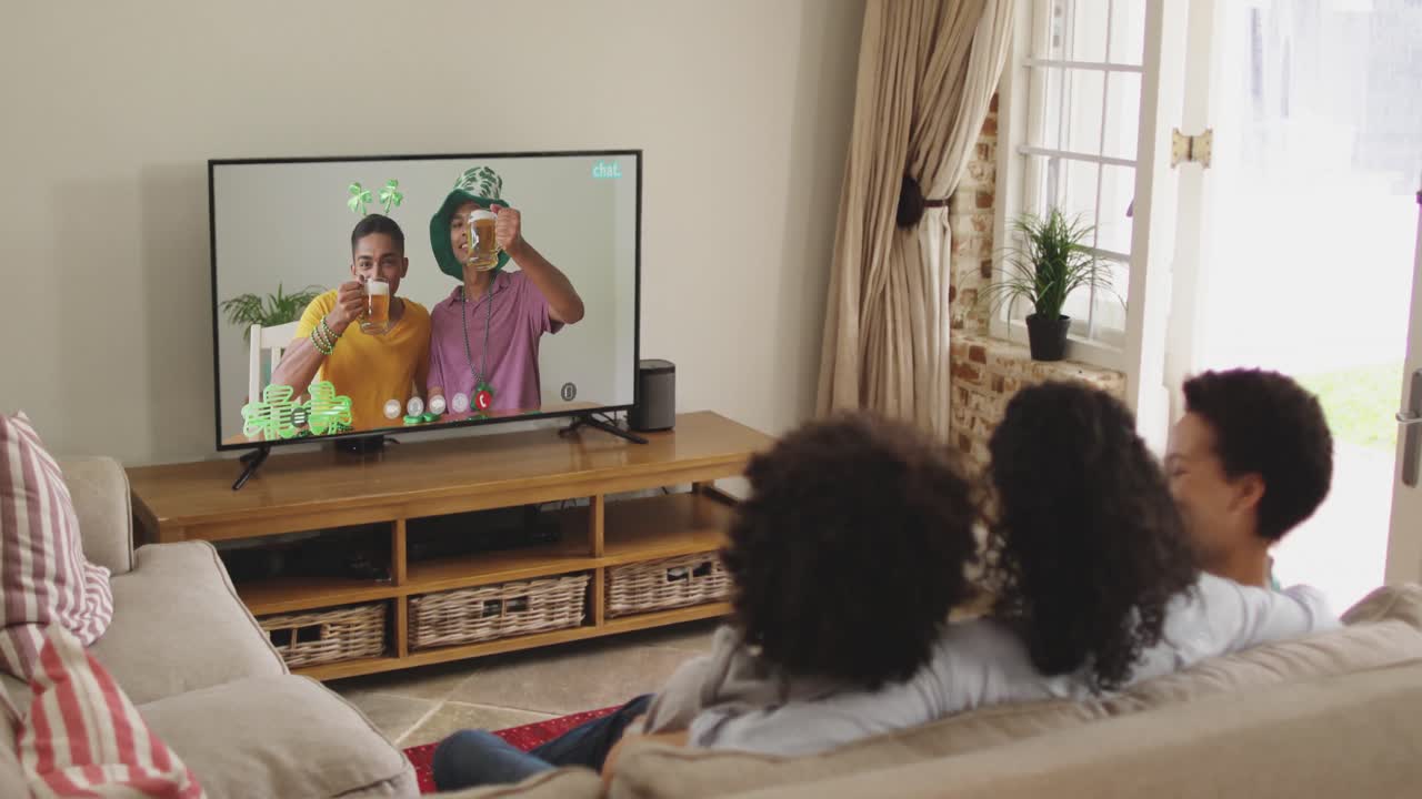 Famiglia afroamericana a casa che usa la smart TV per fare una videochiamata nel giorno di San Patrizio.