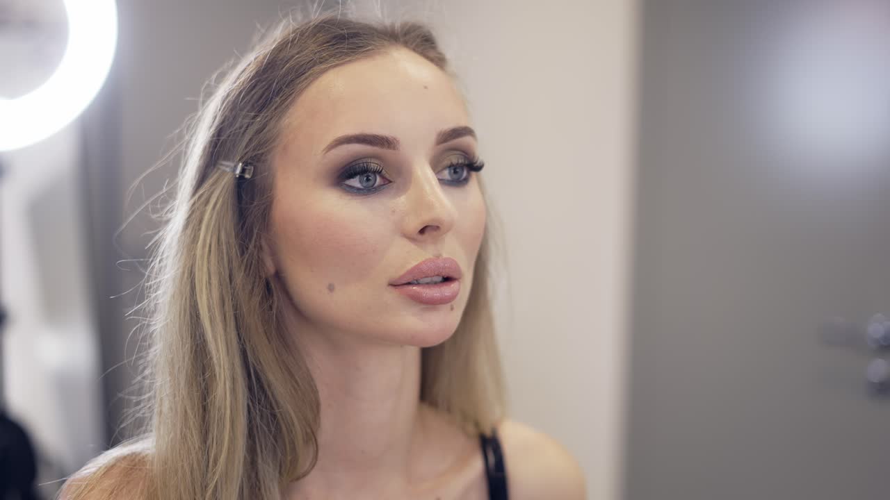 el artista de maquillaje aplica el polvo de acabado en un estudio brillante, cámara lenta