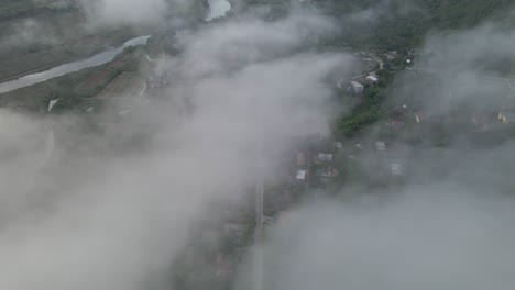 Drohne-Bewegt-Sich-Zwischen-Den-Wolken,-Um-Das-Darunter-Liegende-Dorf-Zu-Enthüllen