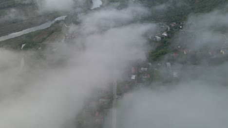el dron se mueve entre la nube para revelar el pueblo debajo