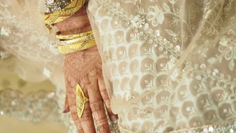 woman's hand with gold jewelry and henna