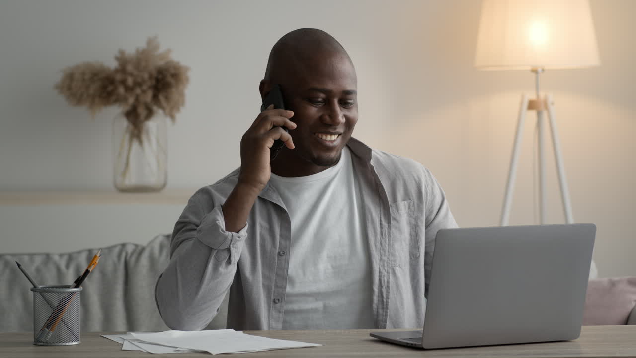 Man Working on Laptop and Talking on Phone