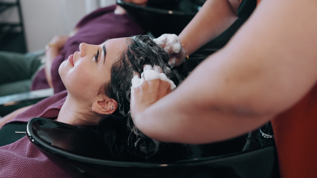 Giovane donna che si fa lavare e massaggiare i capelli in un salone di bellezza