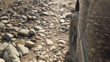 Low-close-up-shot-of-a-tire-off-road-driving-over-rocks