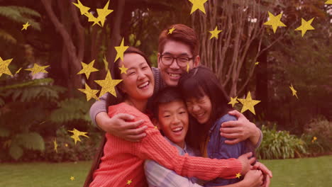 animation of gold stars over smiling asian parents, son and daughter embracing in garden