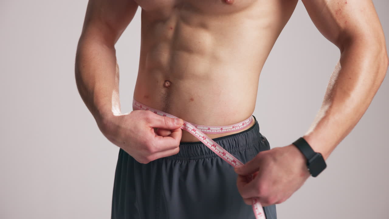 Shirtless Man Measuring His Waist with a Tape Measure