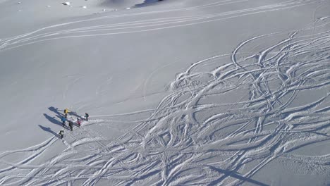 Aerial-view-around-a-group-of-people-meeting-on-powder-snow-slopes,-in-sunny-Tyrol