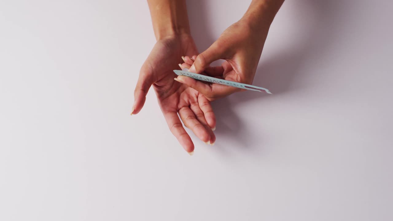 Video di mani di donna caucasica che tiene un cerotto con pillole su sfondo bianco
