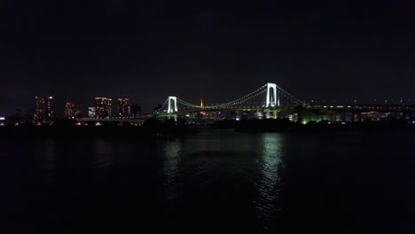 Aerial-view-of-rainbow-bridge-at-night-time-over-water