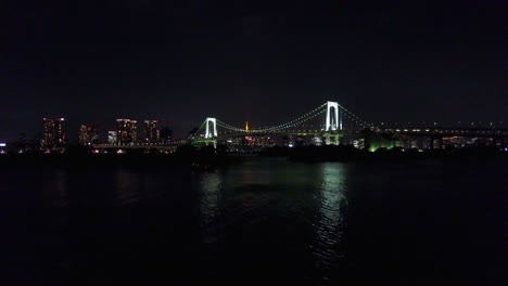 Vista-Aérea-Del-Puente-Del-Arco-Iris-En-La-Noche-Sobre-El-Agua