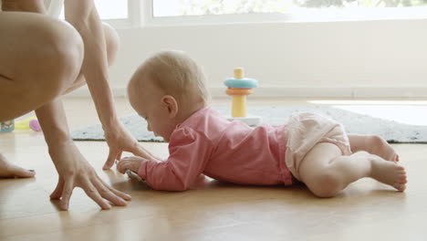 bebé gracioso arrastrándose por el suelo de papá a mamá y tomando el teléfono