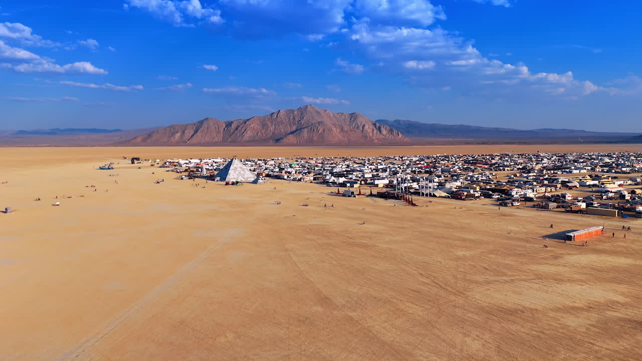 Panoramic View of Desert Festival City and Distant Mountain. A sweeping, panoramic view captures the dense temporary festival city set against