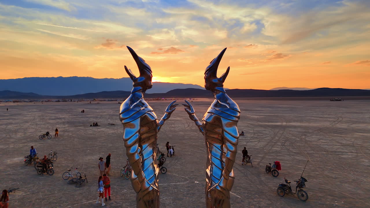 Nevada, USA, 14 August 2025: Metallic twin sculptures at Burning Man festival in Nevada desert.. Two tall metallic sculptures face each other as the sun sets