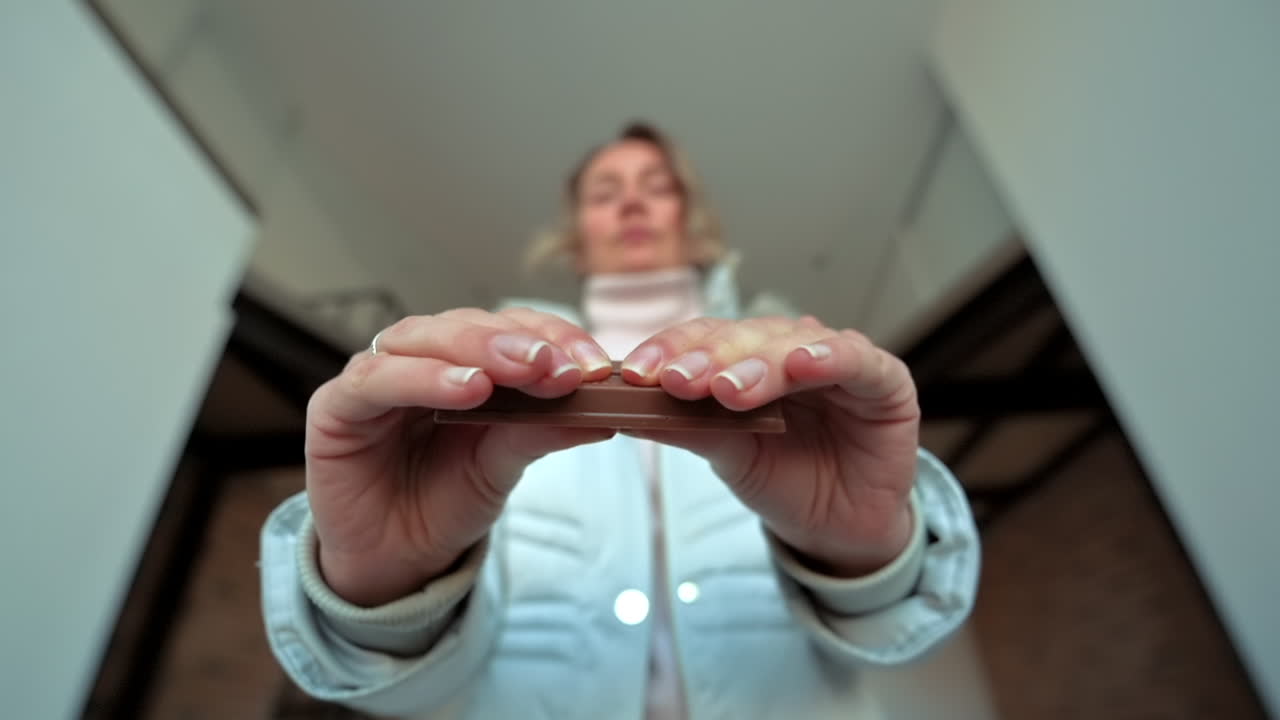 Woman breaking a chocolate covered wafer bar in slow motion