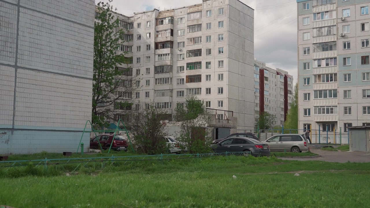 Vista de prédios de apartamentos de vários andares e carros estacionados em um pátio residencial