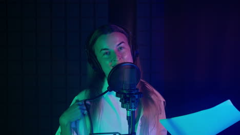 mujer grabando voces en un estudio iluminado con neón