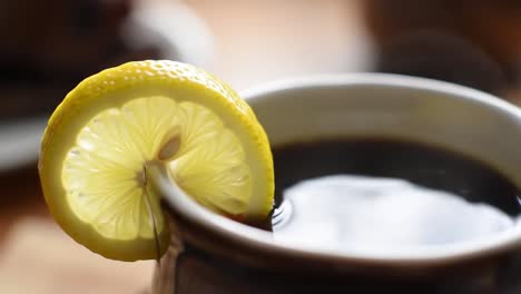 a close-up of a revitalizing beverage: fresh lemon slices infusing flavor into a dark brew, perfect for a refreshing experience