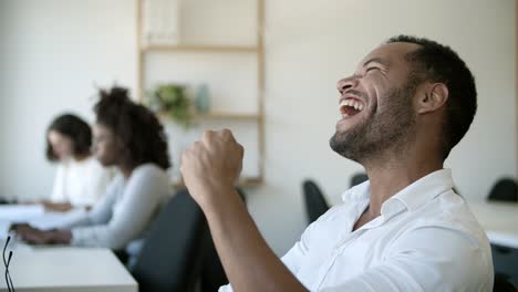 seitenansicht eines fokussierten jungen mannes, der auf dem laptop schreibt und dann lacht