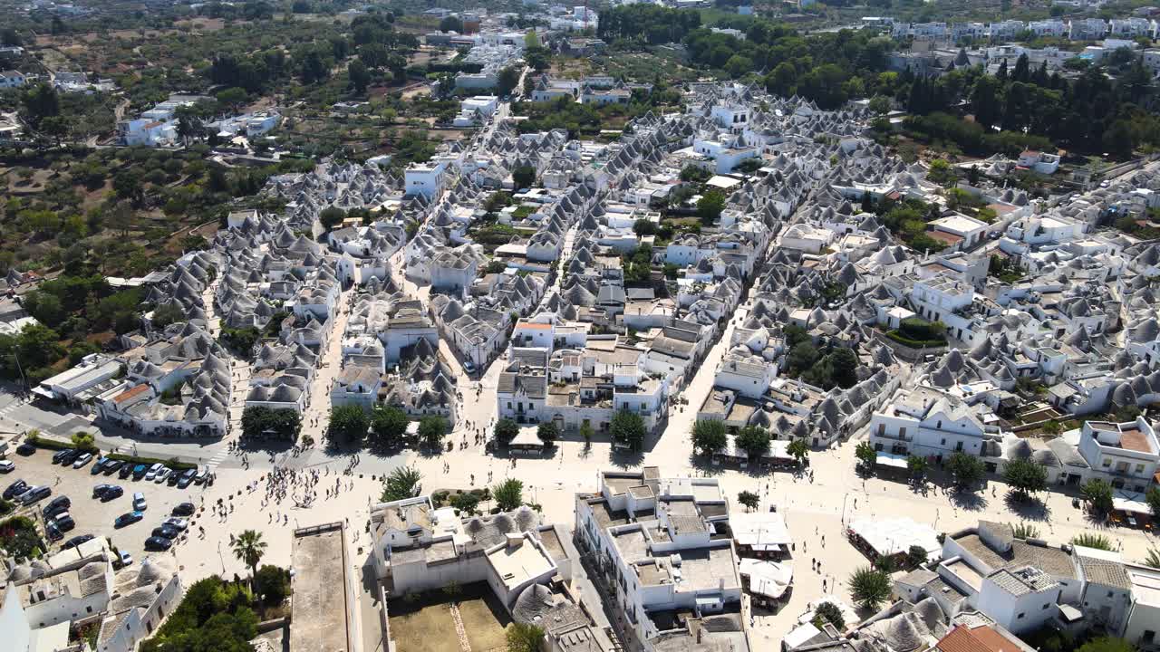 Ampia ripresa aerea con drone che si avvicina alla splendida città di Alberobello, Italia