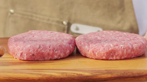 raw burger patties on wooden cutting board