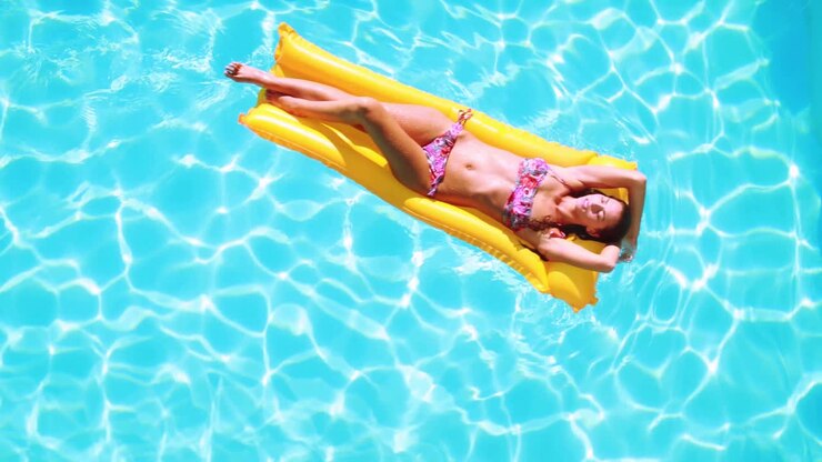 Overhead of brunette lying on lilo in pool on sunny day