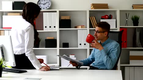 hombre de negocios bebiendo café y discutiendo negocios con la secretaria sentada en la mesa