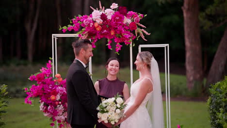 happy bride and groom smiling with celebrant at altar for outdoor wedding ceremony, 4k slow motion