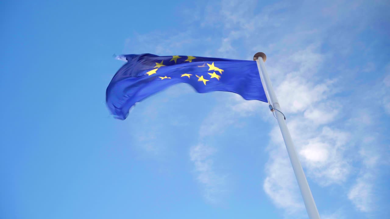 mirando la bandera de la ue ondeando sola con fuerte viento en un cielo azul y nublado, símbolo de la alianza de la unión europea