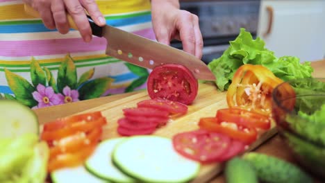 women's hands housewives cut with a knife fresh tomato on the cutting board of the kitchen table