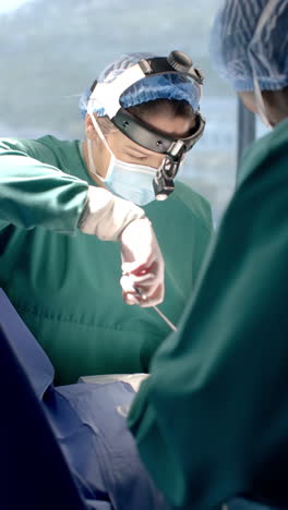 vertical video of caucasian female surgeon wearing headlight during operation, slow motion