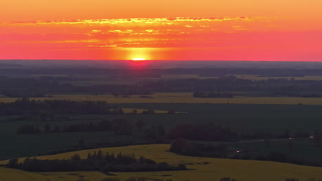 a vivid red sky glows at sunrise or sunset behind a serene landscape in a pedestal shot.