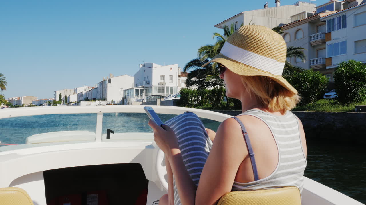 mujer siempre conectada con un teléfono en la mano en un barco que flota en el canal de la ciudad turística de e