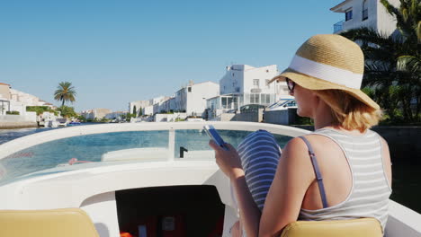 mujer siempre conectada con un teléfono en la mano en un barco que flota en el canal de la ciudad turística de e