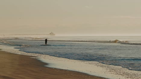 Weitwinkelaufnahme-Mit-Mystischer,-Nebliger-Atmosphäre-Am-Strand-Mit-Brechenden-Wellen-Und-Steg-Im-Hintergrund