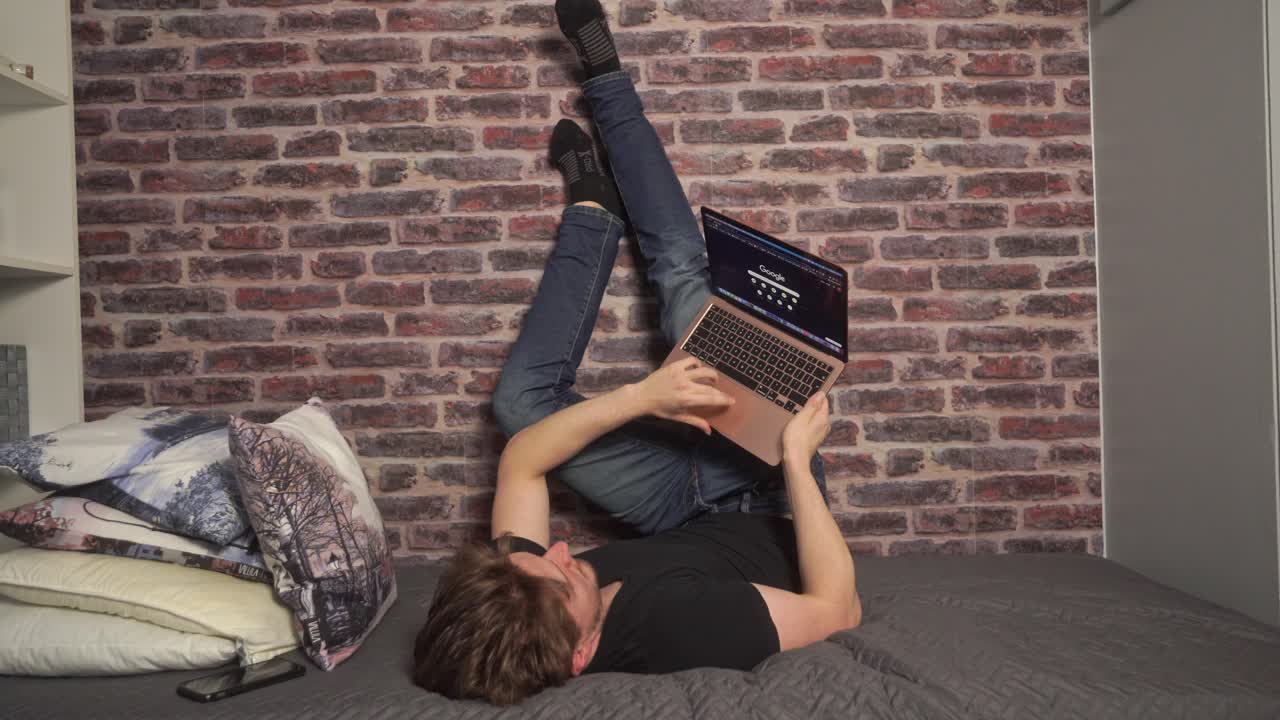 A student rests his feet and legs up against a wall when doing computer work