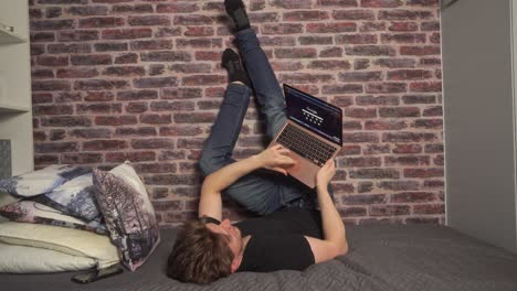 a student rests his feet and legs up against a wall when doing computer work