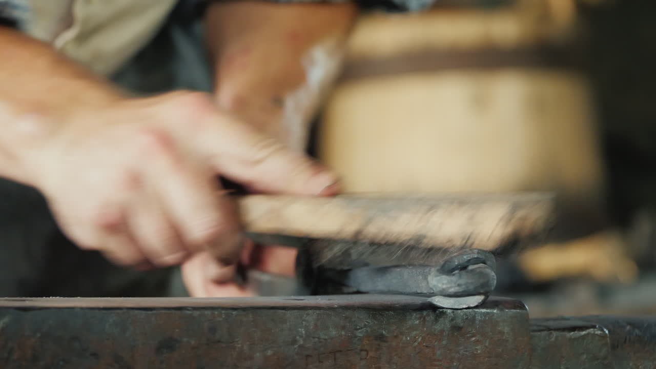 un herrero con un cepillo de metal limpia la pieza de trabajo de escala y artesanía artesanal de escombros