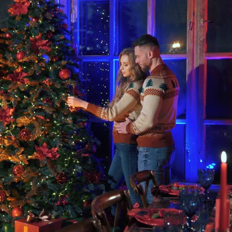 beautiful cheerful young couple in love decorating christmas tree indoors. new year holidays spirit video