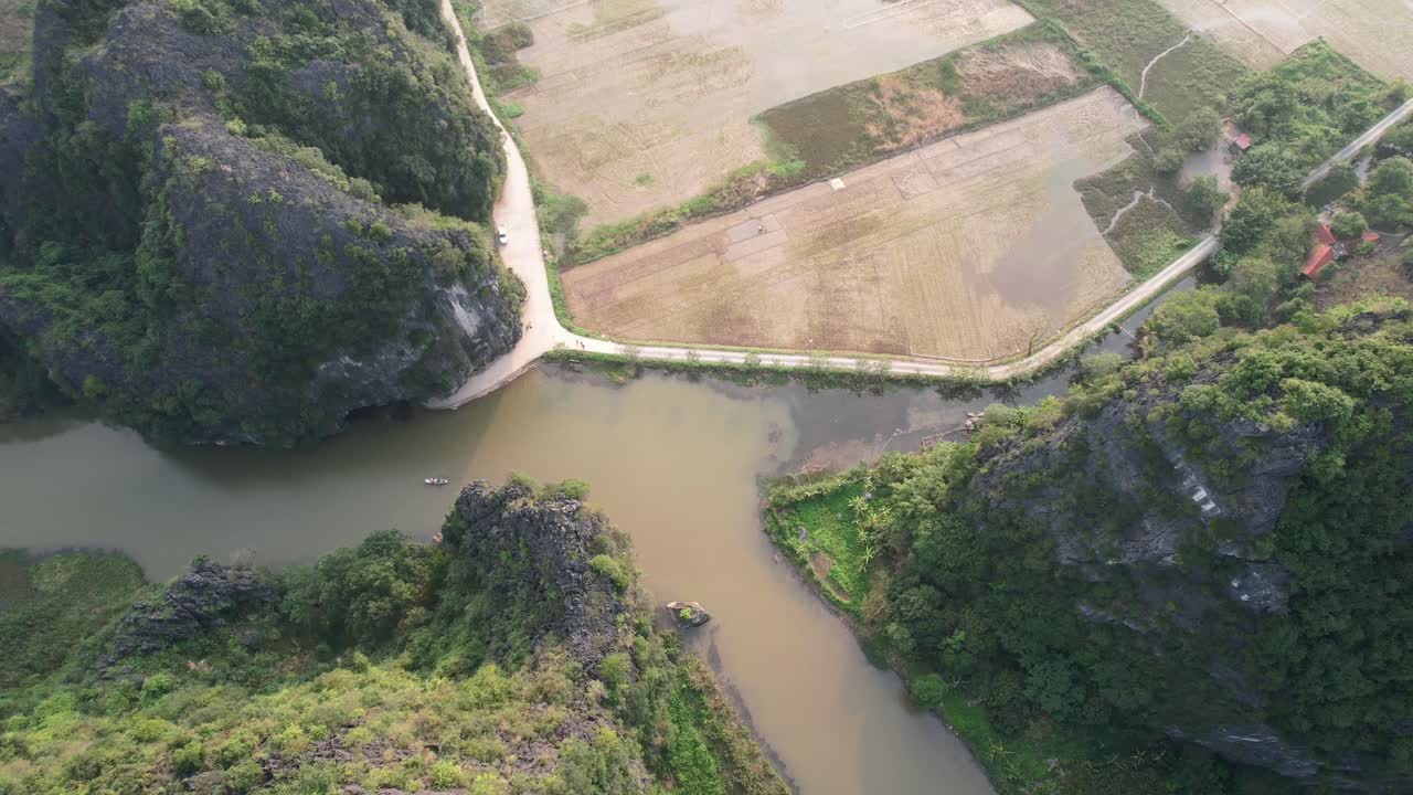 석회암 산맥의 정상과 가파른 경사면 위를 날고 일몰 때 베트남 닌빈의 응오동 강에서 기울어진다