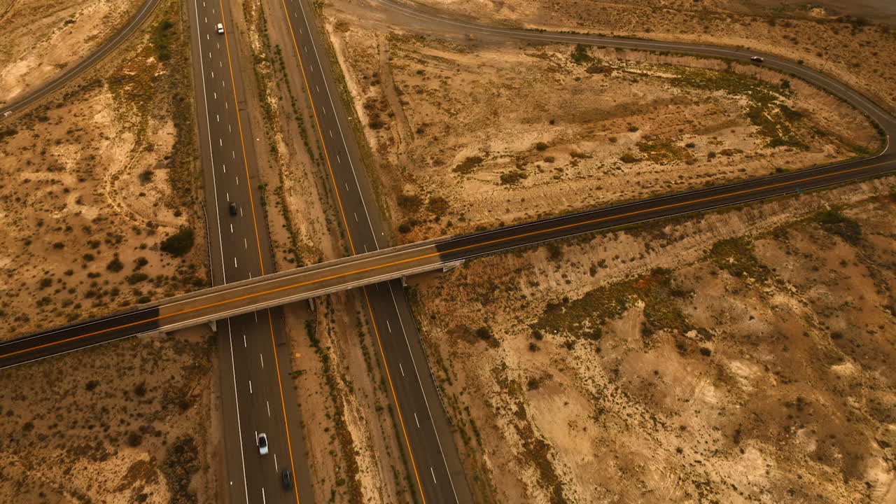 Speedways and freeways built in the desert of California. Cars driving by the roads. Aerial view.
