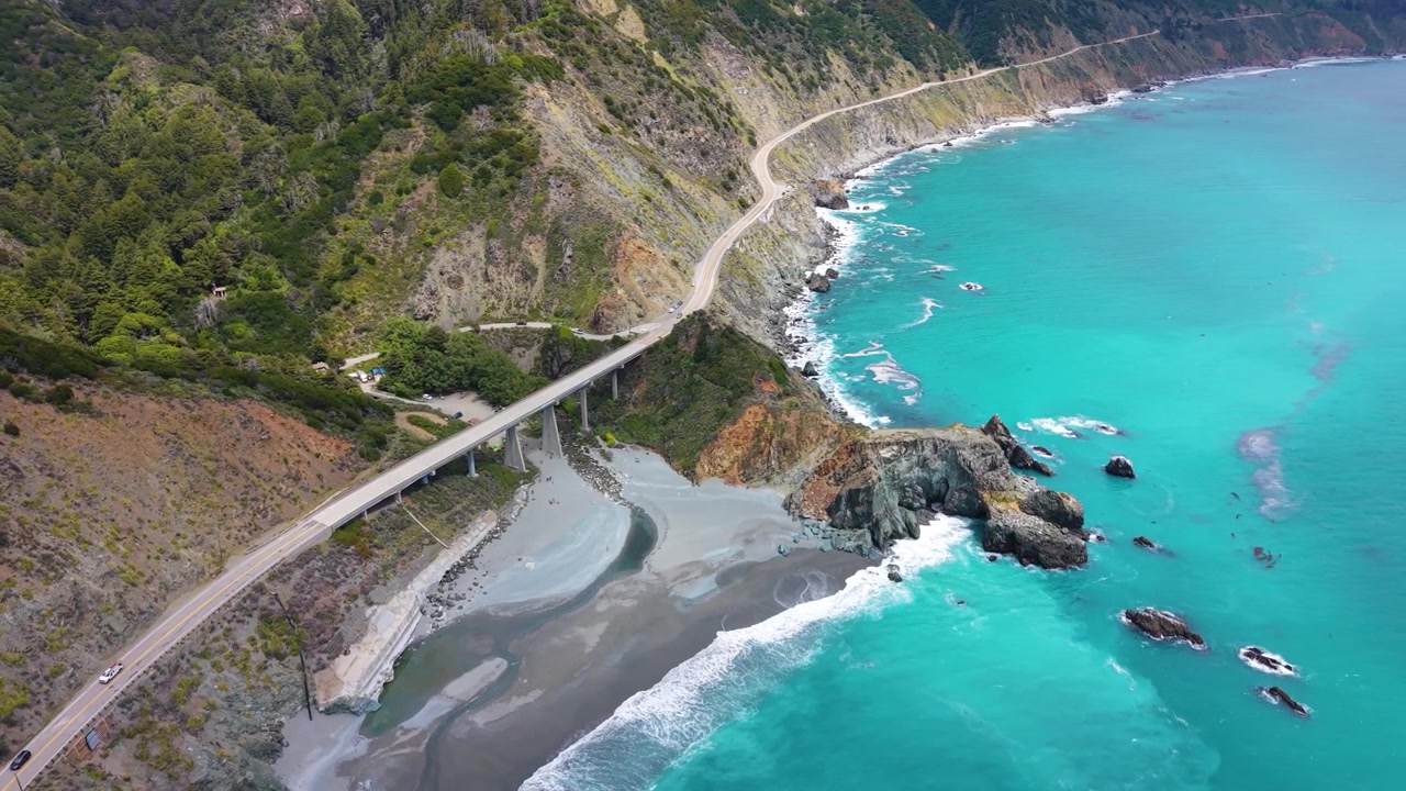 Vista aerea con drone dell'iconico Ponte Bixby Creek che attraversa un canyon lungo la Highway 1 con acqua oceanica turchese sottostante