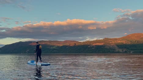 Junger-Mann,-Der-Auf-Einem-Stand-Up-Paddleboard-Auf-Einem-Friedlichen-Loch-Lomond-Paddelt